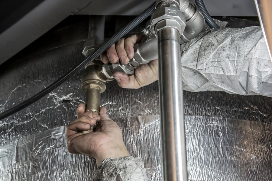 Mains gantées serrant un raccord sur des canalisations en acier isolées